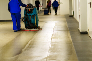 A worker at the airport washes the floor with a special machine