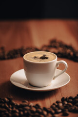 Fototapeta premium Taza de café, taza blanca, rodeado de granos de café, en mesa de madera, mesa de café, en la mañana