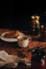 Taza de Café en una mesa de café de madera, con bollos de chocolate, granos de café, molinos de café, rústico