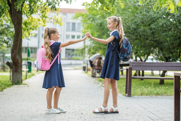 Two happy children met near school with backpacks. Concept of back to school, learning, friendship