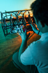 Male programmer adjusting cryptocurrency mining rig to optimal settings with mobile phone