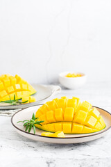 Ripe mango cubes on plates on the table. Tropical fruit. Vertical view