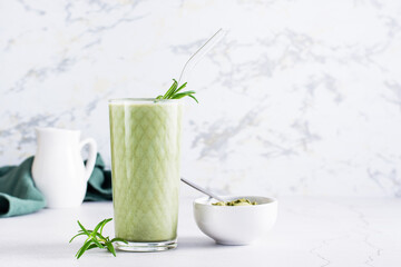 Matcha latte in a glass and powder in a bowl on the table. Homemade trendy drink