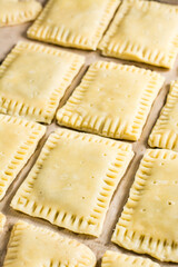 Raw homemade pop tarts on a baking sheet ready to bake. Vertical view