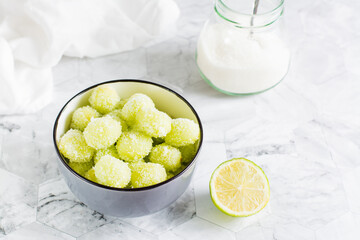 Sour candy grapes in a bowl, lime and sugar for cooking on the table. Social media candy trend.