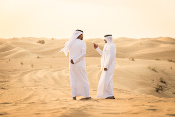 Arabic men in the desert of Dubai wearing traditional emirates clothing