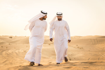 Arabic men in the desert of Dubai wearing traditional emirates clothing