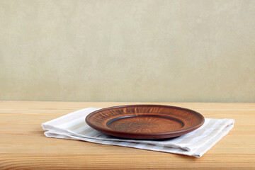 An empty wooden table with a clay bowl and a striped tablecloth.