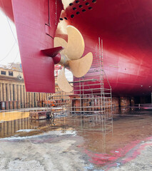 Dry-cargo ship in dry dock for repairs and maintenance at a shipyard.
