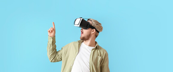 Young man with VR glasses on light blue background