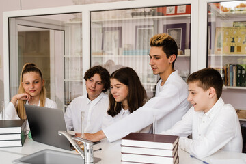 Obraz premium Discussion with a teacher at a chemistry lesson in a laboratory. Group of classmates are discussing chemistry experiments and homework at school. Education concept.