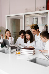 Education. Chemistry teacher helps explain theory in class at chemistry lesson in laboratory. Communication between teacher and students. Preparing homework.