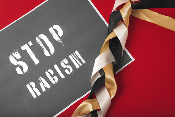 Braided ribbons and paper sheet with text STOP RACISM on color background