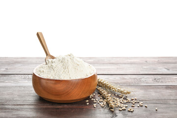 Bowl with flour, scoop and wheat ears on wooden table against white background