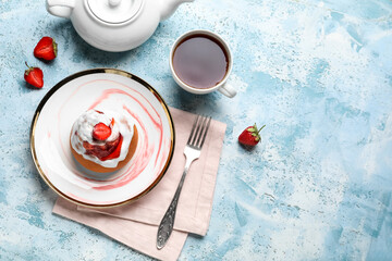 Plate with strawberry cinnamon roll, teapot and cup on table