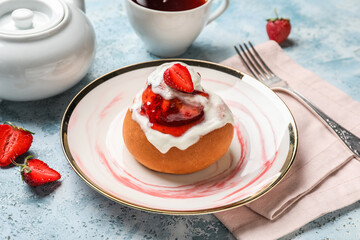 Plate with strawberry cinnamon roll and cup of tea on grunge background