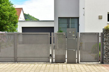 Sichtschutzwand aus Metall mit Tor im Eingangsbereich als Grundstücksabgrenzung vor einem Wohnhaus