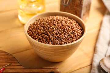 Bowl with dry buckwheat grains on wooden table