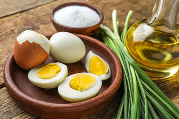 Bowl of boiled chicken eggs and green onion on wooden table, closeup