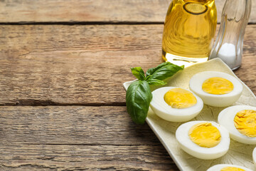 Plate with halves of boiled chicken eggs on wooden background, closeup