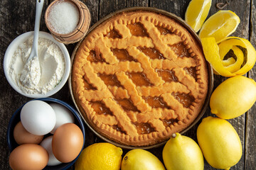 Delicious lemon tart, pie with cooking ingredients on the wooden table, fresh lemons fruits around	
