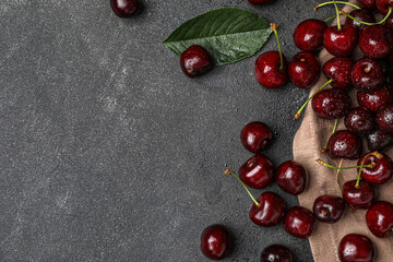 Tasty ripe cherries with water drops on dark background