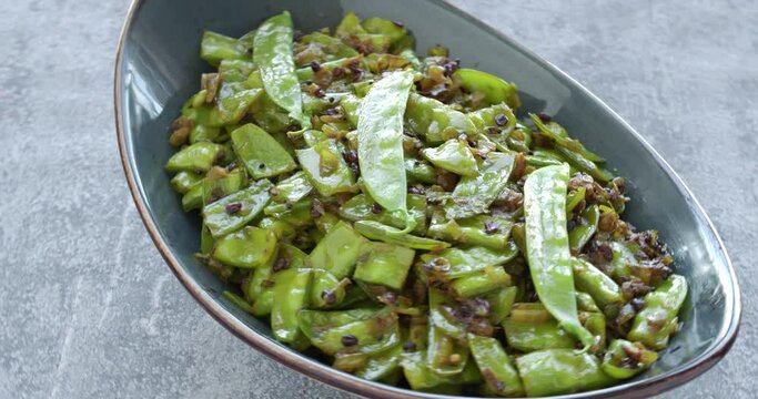 Sugar peas vegetable poriyal (sugar peas thoran) dish. Asian cuisine style meal. Table spin.