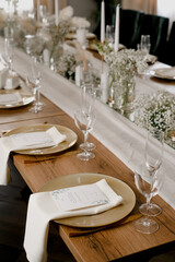 Aesthetic table setting in the restaurant for the holiday with flowers and gold, glasses
