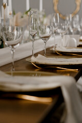 Aesthetic table setting in the restaurant for the holiday with flowers and gold, glasses