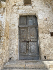 Fototapeta na wymiar ancient wooden brown doors on the side of ancient white stone building