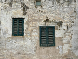 Shuttered door and window on side of ancient stone building 