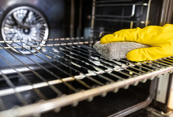 Hands with gloves wiping oven wire