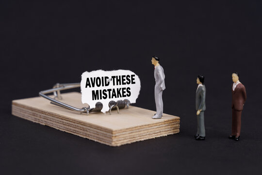 Figures of businessmen stand near a mousetrap, the bait in which is torn paper with the inscription Avoid These Mistakes - Powered by Adobe