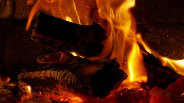 Close up slow motion view of flames from fireplace. Night bonfire, wooden logs on fire, sparks fly from burning fire. 4K footage of RED camera Super slow motion of flames isolated on black background