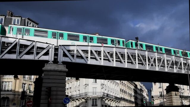 Passage of the Parisian subway (m&eacute;tropolitain) in the middle of the city in Paris, France. The metro is sunny, with a threatening sky in the background.
