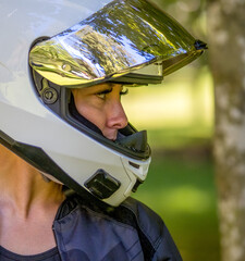 Side profile view of a young pretty female motorcyclist with full face helmet