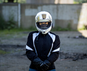 Young pretty female motorcyclist with full face helmet standing with full protective gear on