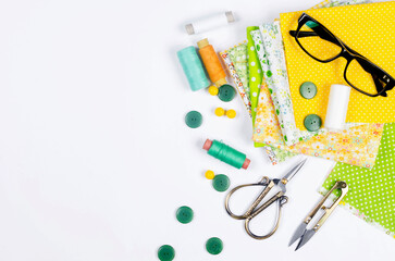 Accessories for sewing and needlework. Fabric, spools of thread, scissors and glasses.