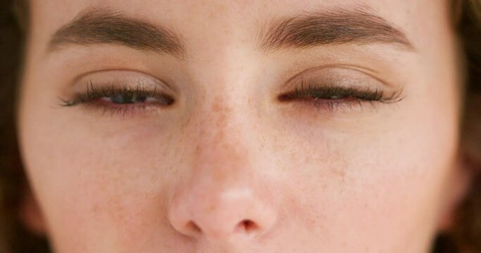 Closeup face of a young emotional woman with tears in her eyes. Portrait of a sad female crying with pain and hurt in her eyeballs. A tired lady tearing up with a bit of redness due to allergies