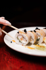 sushi roll set on white plate with chopsticks and caviar