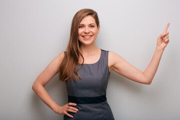 Smiling business woman office worker in gray dress pointing finger up. isolated female business person portrait.