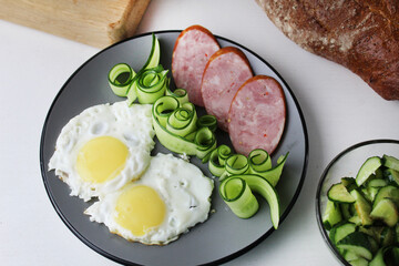 zastrak eggs scrambled eggs sausage salad cucumbers on the trael view from the side top. Traditional English American breakfast. First meal. The benefits of proper nutrition Egg Day. Egg dishes