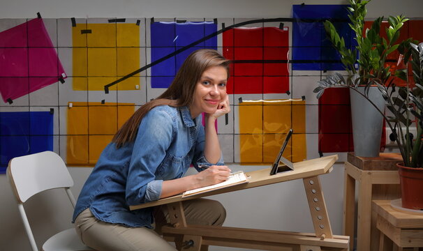 Smiling Student Woman Designer Learning With Grafic Tablet And Pen, Wall With Color Palette.