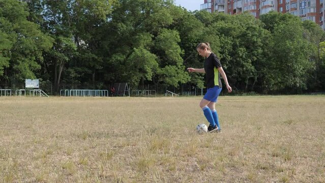 a girl dribbles a ball across an unmowed field