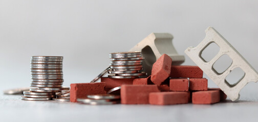Business concept with coin and miniature red brick. Concept about construction material cost.
