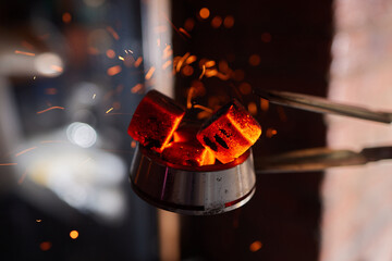 Burning red coals for hookah during preparation. - obrazy, fototapety, plakaty