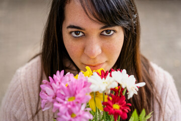 Close-up portrait of a young Latin woman holding a bouquet of flowers