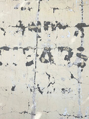 Letters on a White Brick or Concrete Wall with Peeling Paint