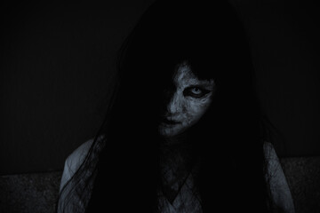 Fototapeta na wymiar Asian woman ghost or zombie horror creepy scary close up she face and hair covering the face her eye looking to camera at night, Halloween day concept, in dark tone