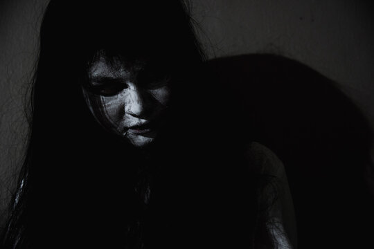 Asian woman ghost or zombie horror creepy scary close up she face and hair covering the face her eye looking to camera at night, Halloween day concept, in dark tone